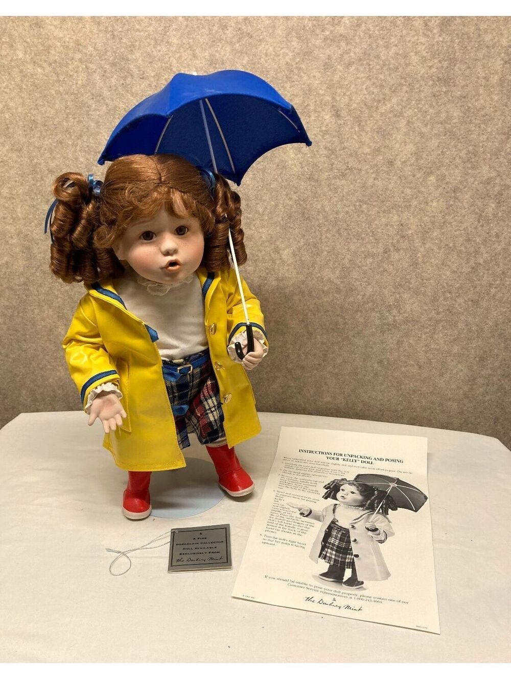 The Danbury Mint 'Kelly' Porcelain Doll with Blue Umbrella and Yellow Raincoat